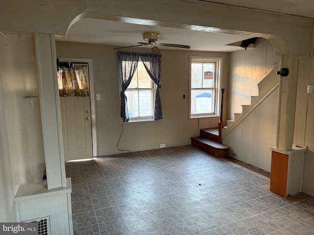 foyer featuring ceiling fan and wood walls