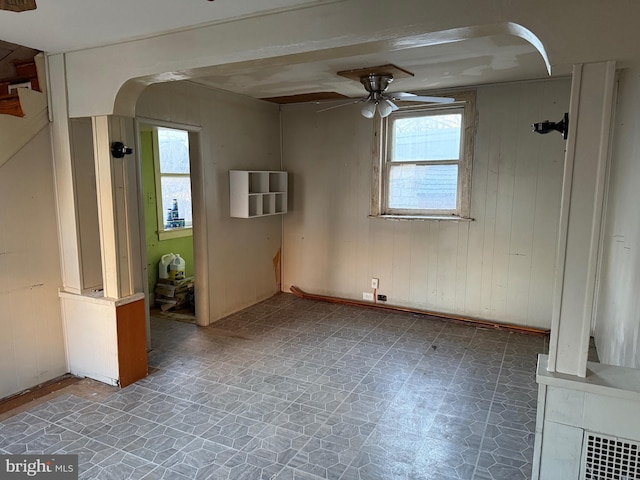 spare room featuring ceiling fan and wooden walls