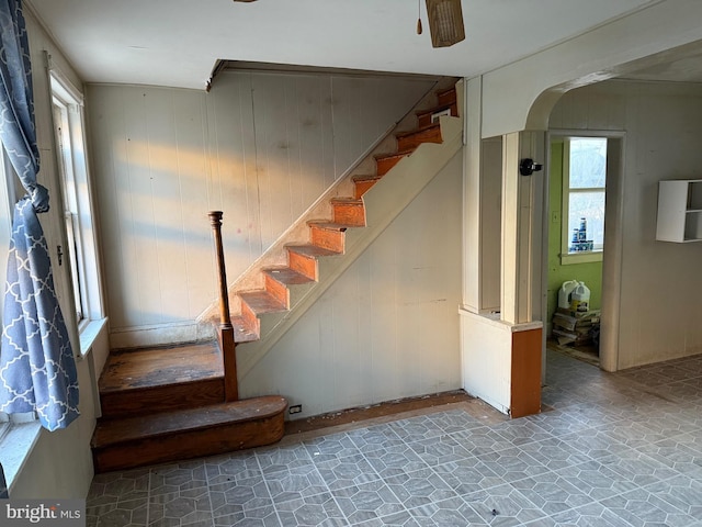 stairway featuring ceiling fan and wood walls