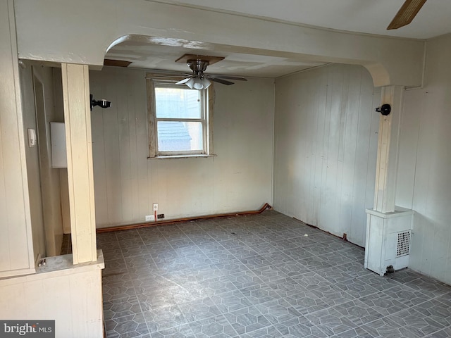 spare room with ceiling fan and wood walls