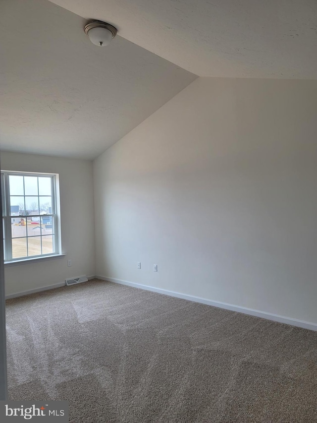 carpeted empty room with lofted ceiling