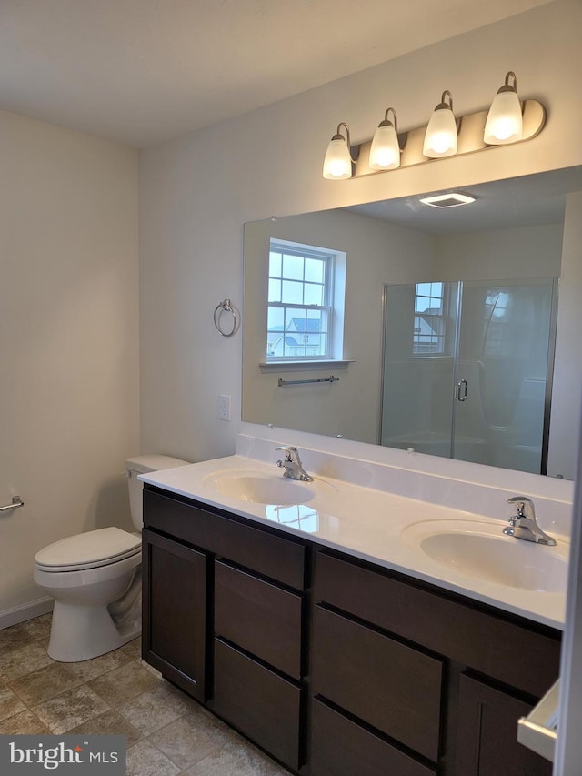 bathroom featuring vanity, a shower with shower door, and toilet