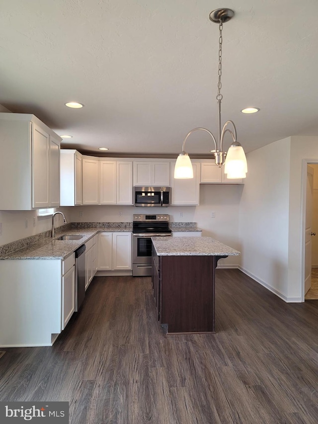 kitchen featuring stainless steel appliances, dark wood-type flooring, sink, pendant lighting, and a kitchen island