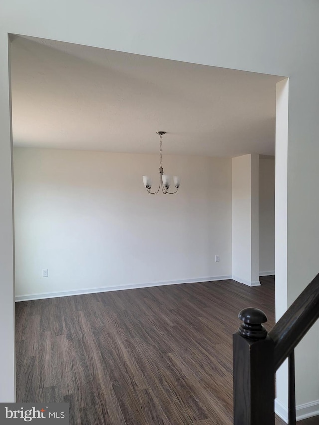 unfurnished room with dark hardwood / wood-style floors and an inviting chandelier