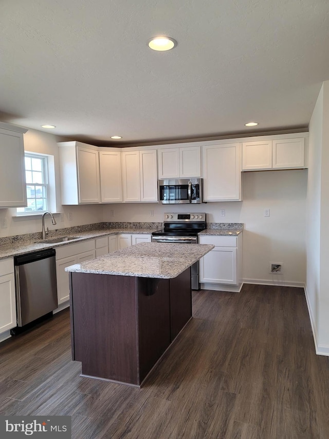 kitchen featuring sink, light stone counters, dark hardwood / wood-style floors, a kitchen island, and appliances with stainless steel finishes