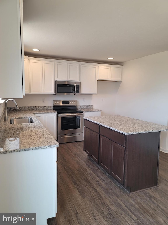 kitchen featuring light stone counters, stainless steel appliances, sink, dark hardwood / wood-style floors, and a kitchen island