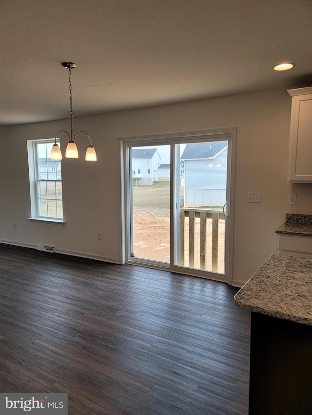 unfurnished dining area featuring a notable chandelier and dark wood-type flooring