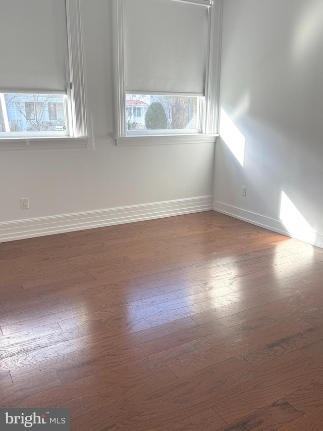 empty room with dark wood-type flooring and baseboards