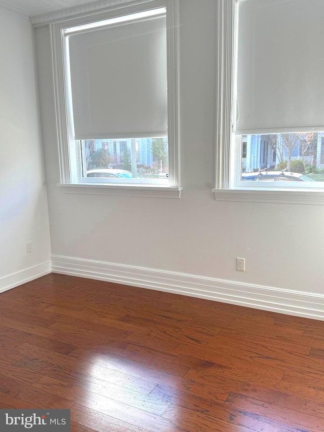 spare room featuring dark wood-style floors and baseboards