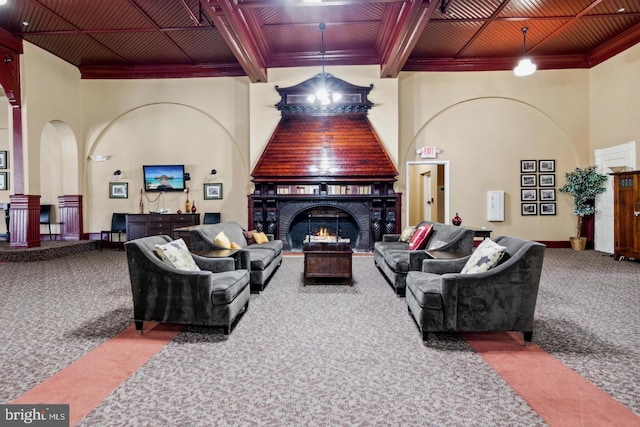 living area with ornamental molding, a warm lit fireplace, carpet flooring, and beamed ceiling