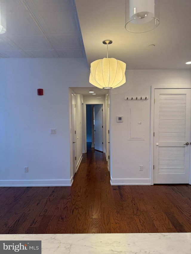 unfurnished dining area featuring dark wood-style floors and baseboards