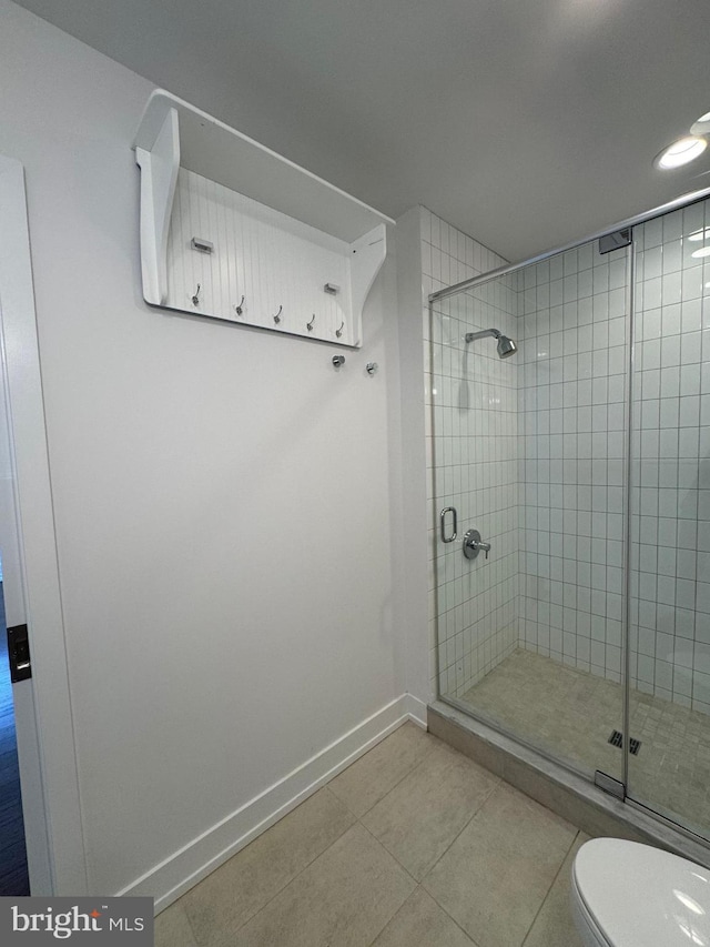 bathroom with tile patterned floors, a shower with door, and toilet