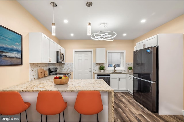 kitchen with kitchen peninsula, tasteful backsplash, stainless steel appliances, decorative light fixtures, and white cabinets