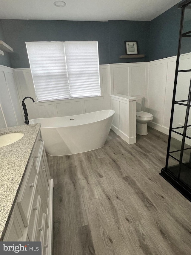 bathroom featuring a tub, vanity, wood-type flooring, and toilet