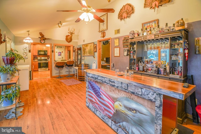 bar with ceiling fan, stove, vaulted ceiling, and hardwood / wood-style flooring