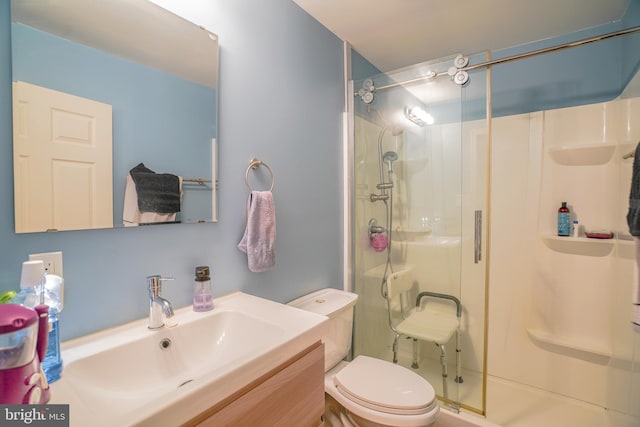 bathroom with a shower with door, vanity, and toilet