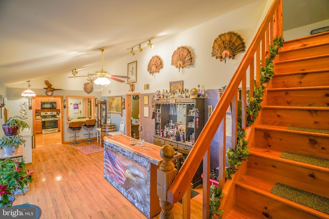 stairway featuring ceiling fan, hardwood / wood-style floors, and lofted ceiling