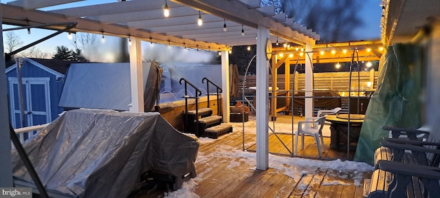 patio terrace at dusk with a pergola, a hot tub, a storage shed, and a wooden deck