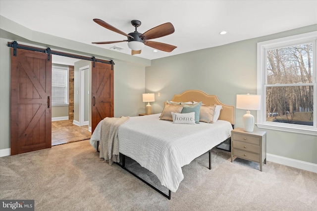 carpeted bedroom with a barn door and ceiling fan