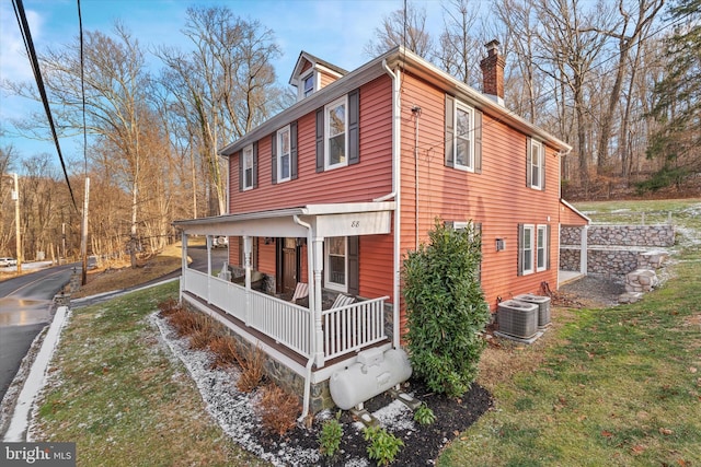 view of side of home featuring a lawn, central AC unit, and a porch