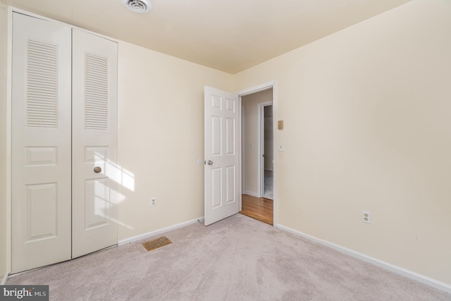 unfurnished bedroom with light carpet and a closet