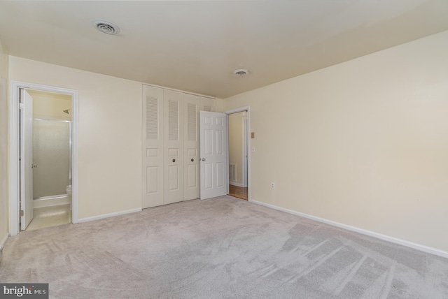 unfurnished bedroom featuring connected bathroom and light colored carpet