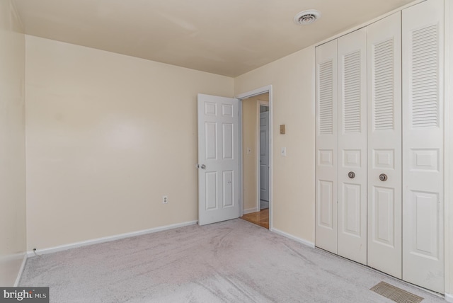 unfurnished bedroom with light carpet and a closet