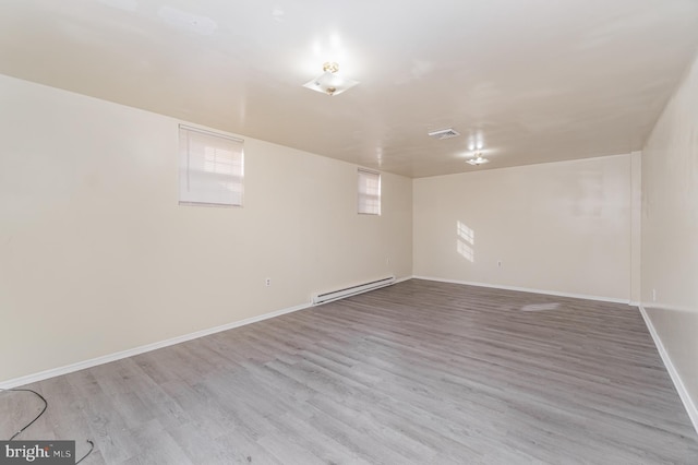 basement featuring light hardwood / wood-style flooring and a baseboard heating unit