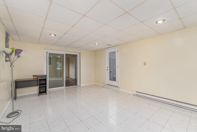 tiled empty room with a drop ceiling and a baseboard heating unit