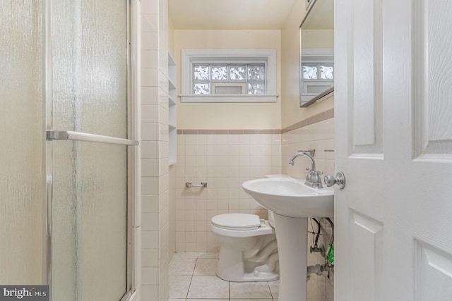 bathroom with tile patterned flooring, toilet, tile walls, and an enclosed shower