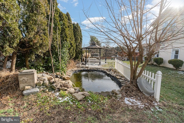 view of yard featuring a gazebo and a small pond