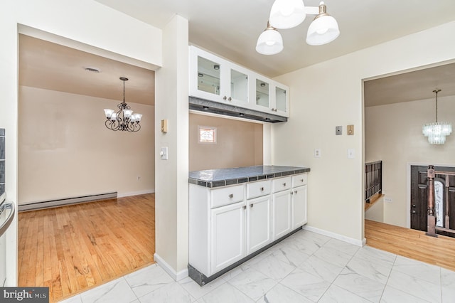 kitchen with white cabinets, pendant lighting, baseboard heating, and an inviting chandelier