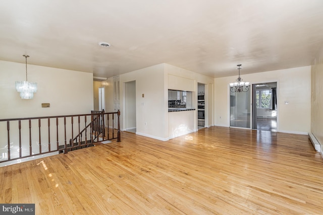 unfurnished living room featuring light wood-type flooring and a notable chandelier