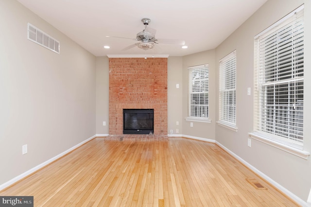 unfurnished living room with a brick fireplace, ceiling fan, and light hardwood / wood-style flooring