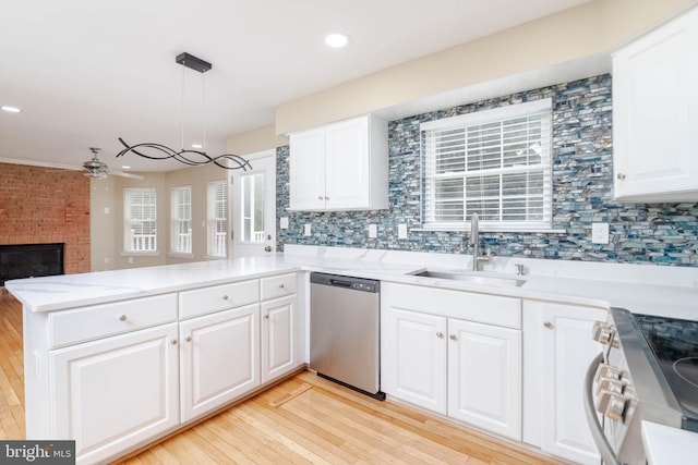 kitchen featuring pendant lighting, sink, appliances with stainless steel finishes, light hardwood / wood-style floors, and kitchen peninsula