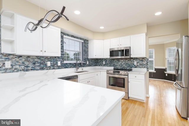 kitchen featuring white cabinets, light hardwood / wood-style flooring, decorative backsplash, appliances with stainless steel finishes, and light stone counters