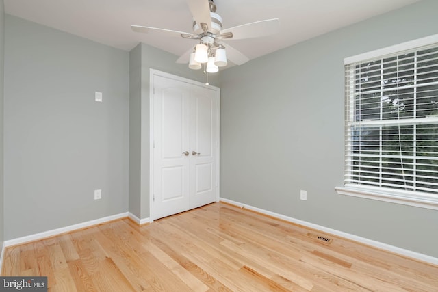 unfurnished bedroom featuring ceiling fan, wood-type flooring, and a closet