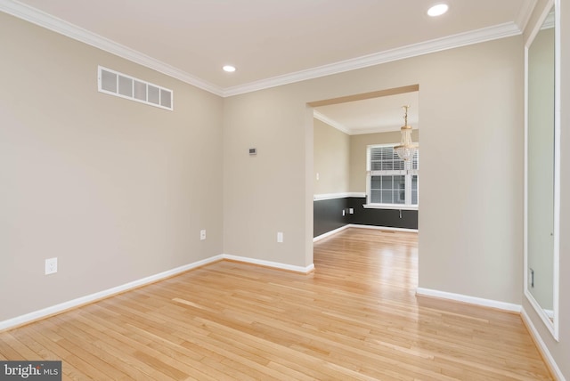 empty room featuring crown molding, wood-type flooring, and an inviting chandelier