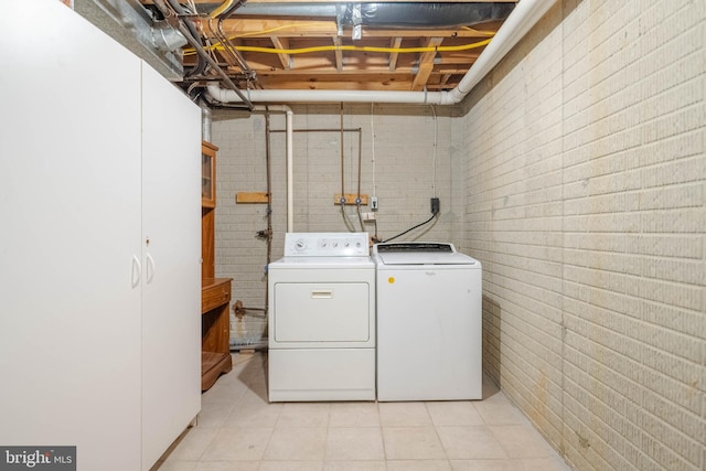 clothes washing area featuring washing machine and dryer and brick wall