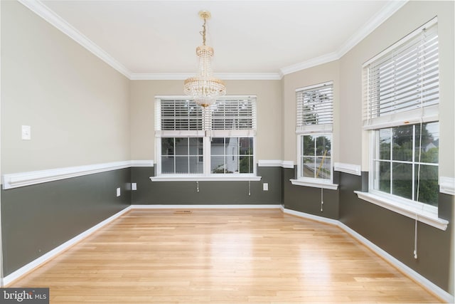 unfurnished dining area with crown molding, a chandelier, and wood-type flooring