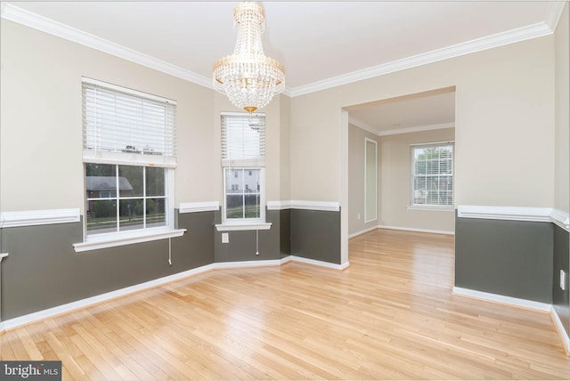 spare room featuring ornamental molding, light hardwood / wood-style flooring, and a notable chandelier