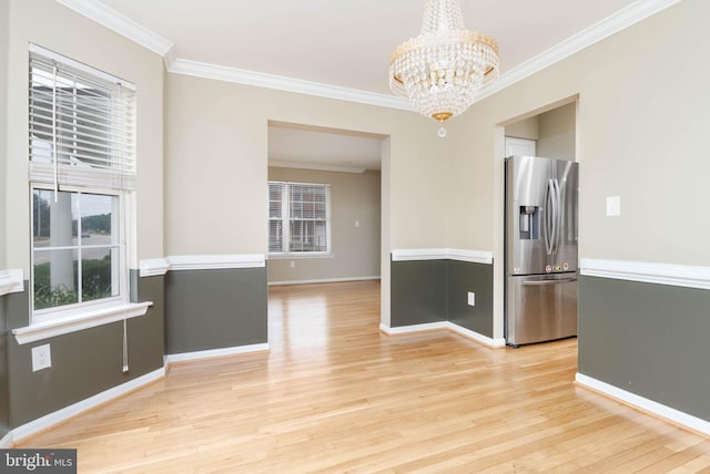 unfurnished dining area with an inviting chandelier, light hardwood / wood-style flooring, and crown molding