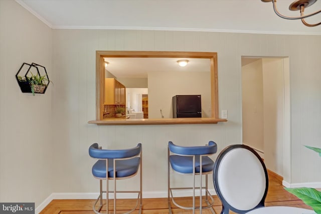 kitchen featuring black fridge, light wood-type flooring, and crown molding