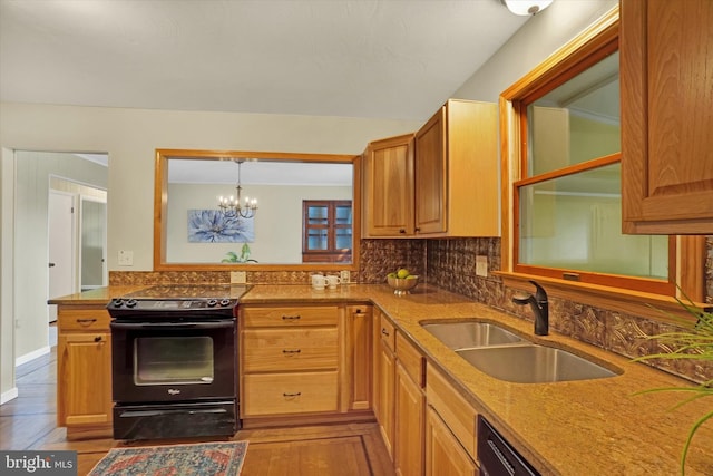 kitchen with tasteful backsplash, black range with electric stovetop, sink, and an inviting chandelier