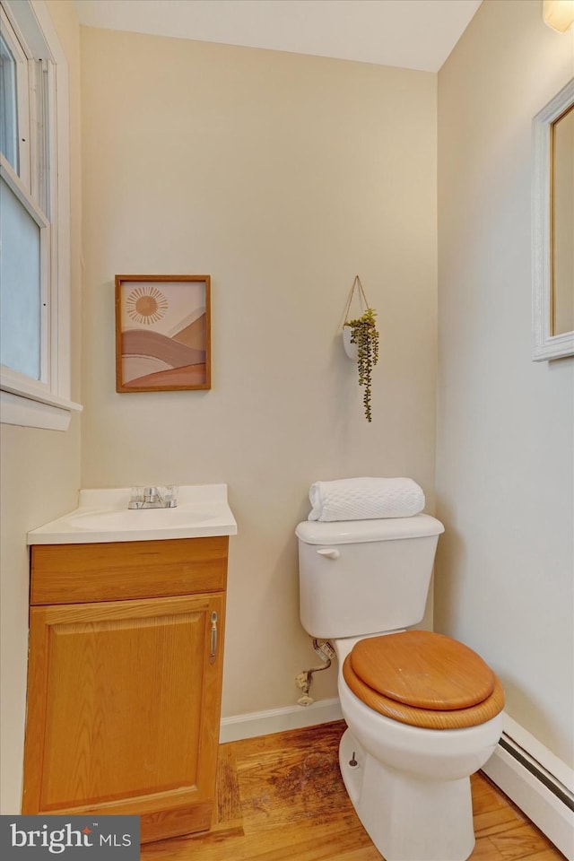 bathroom with hardwood / wood-style floors, vanity, toilet, and baseboard heating