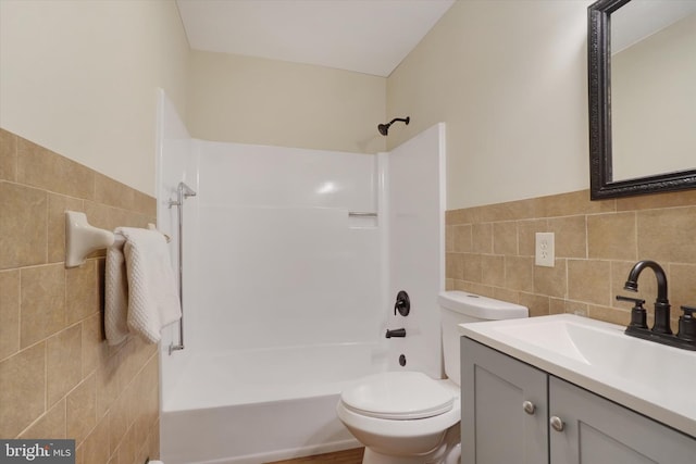 full bathroom with washtub / shower combination, vanity, tile walls, and toilet