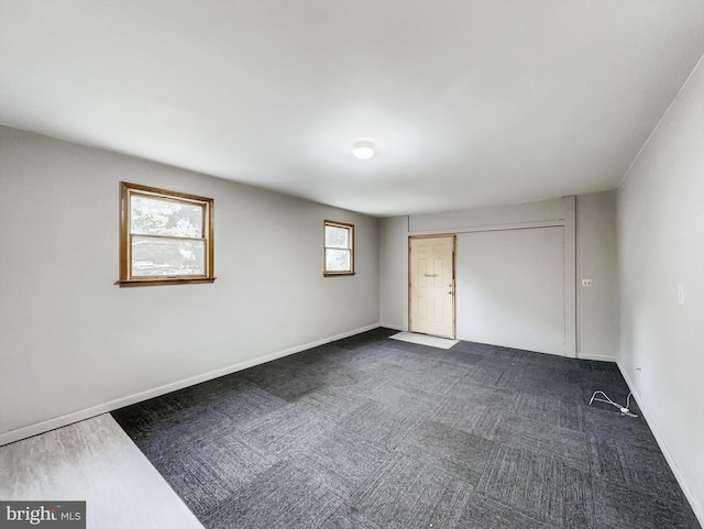 unfurnished bedroom with dark carpet and multiple windows