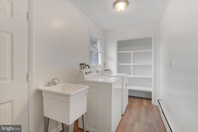 laundry room featuring baseboard heating, washer and dryer, sink, and light hardwood / wood-style floors