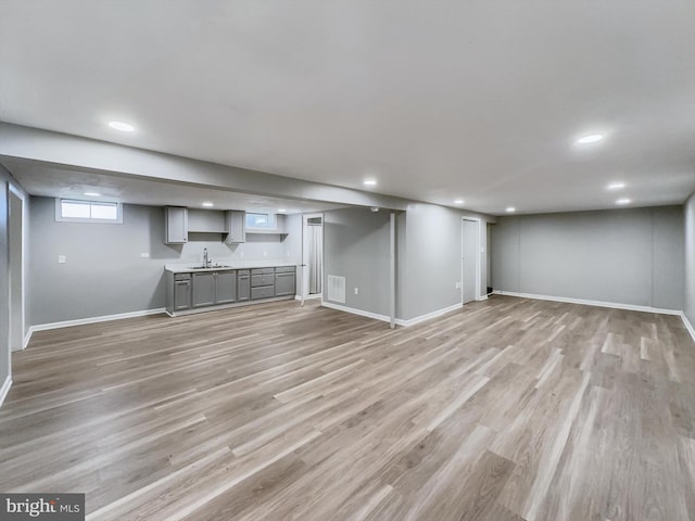 basement with sink and light wood-type flooring