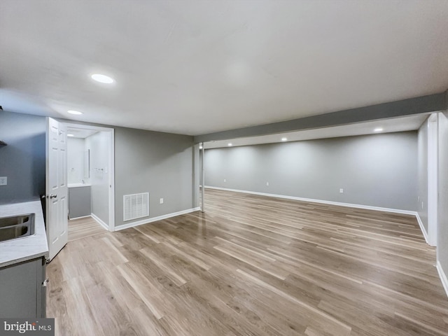 unfurnished living room with light hardwood / wood-style flooring and sink